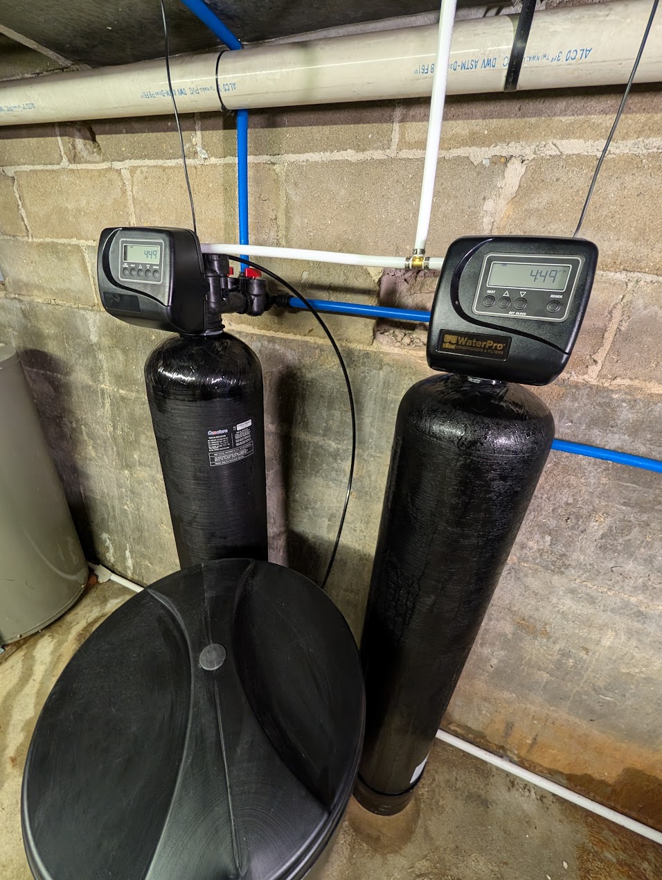 Well water treatment system installed on a basement wall